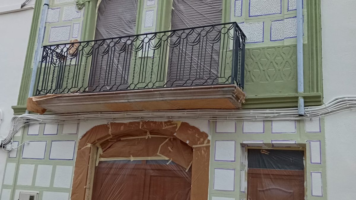 Fachada restaurada con pintura decorativa en verde y blanco